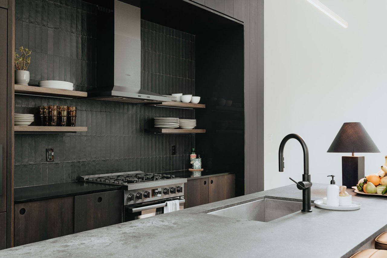 A large kitchen island with a light grey countertop features a modern black faucet over a sink.