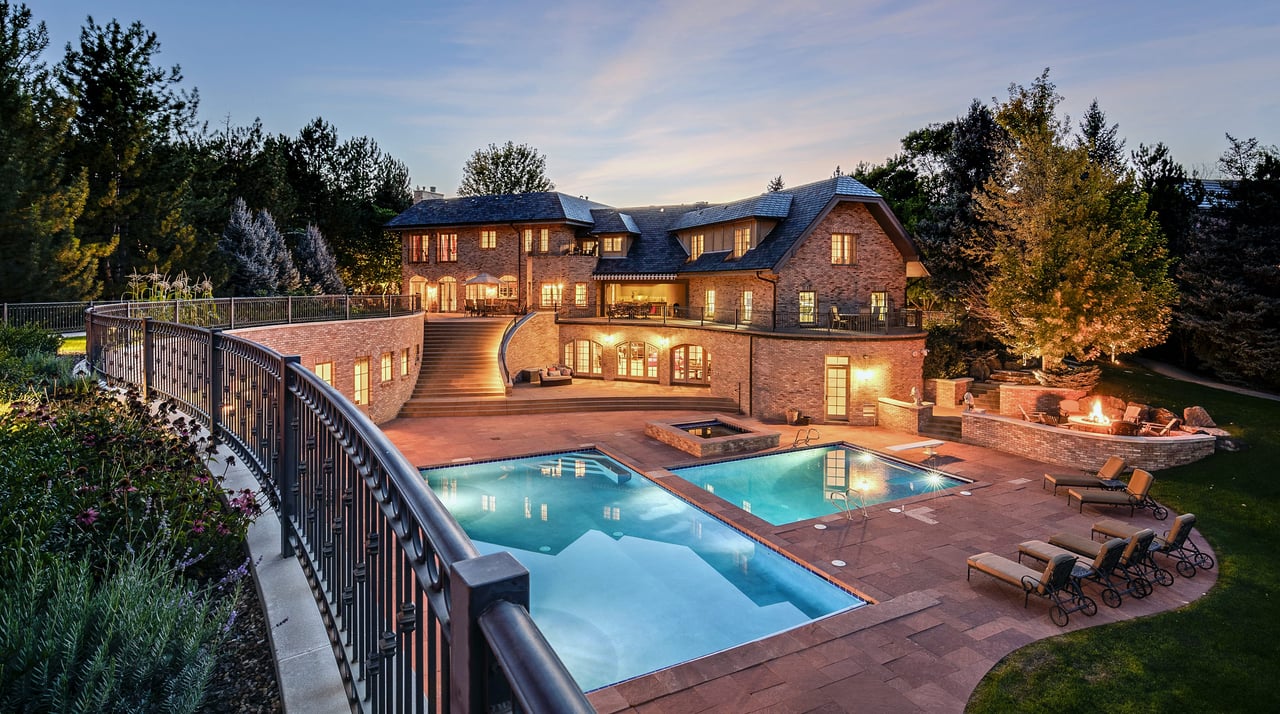 A luxurious mansion with two swimming pools and a fire pit