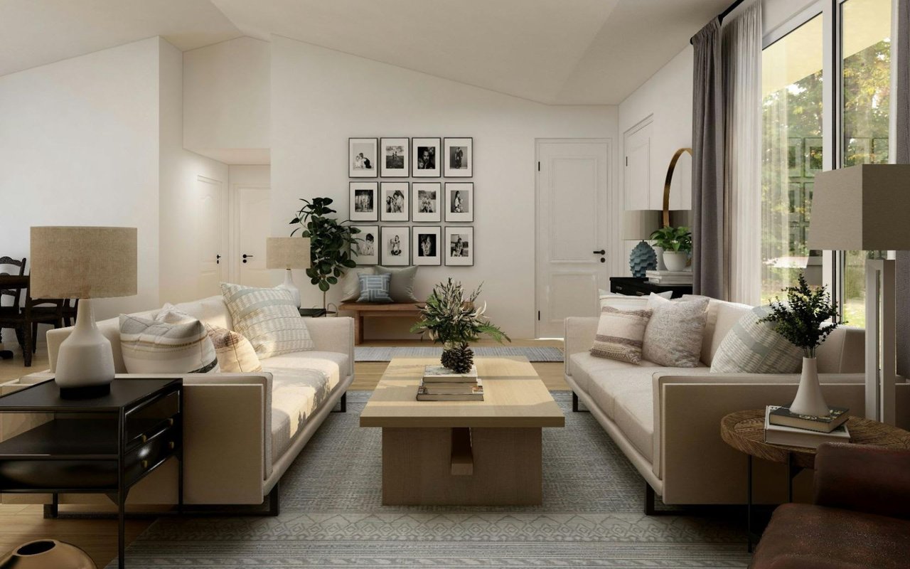 Two cream-colored sofas face each other, separated by a light wood coffee table adorned with a floral arrangement and books. 