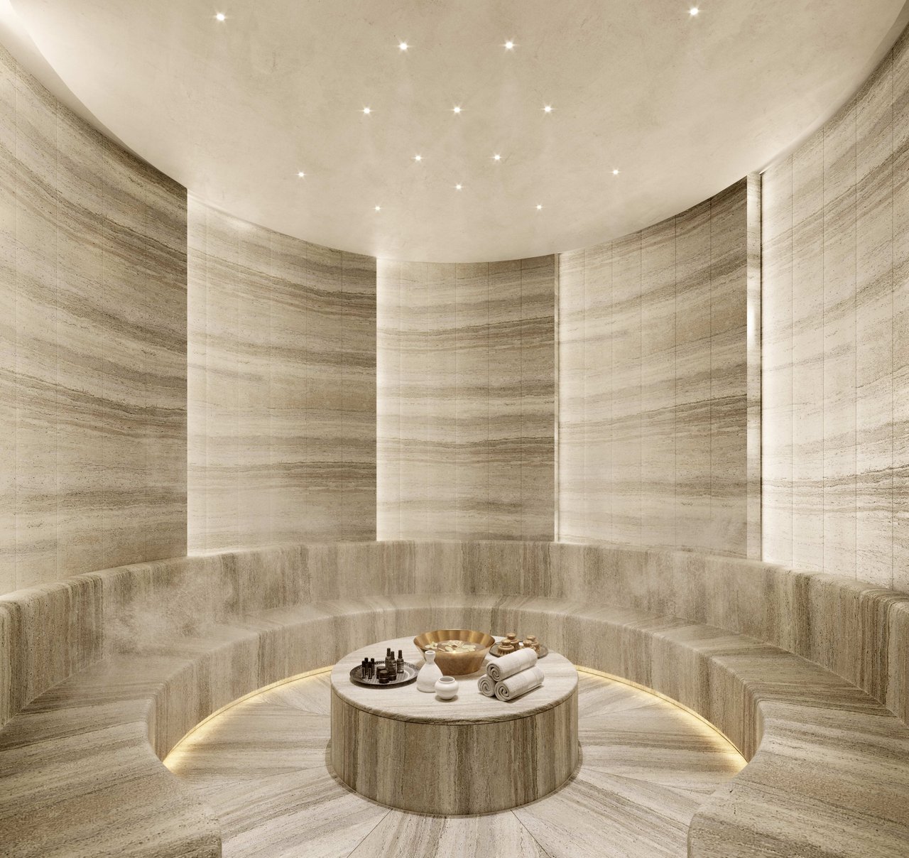 Baccarat spa relaxation room with curved stone seating and a central table set with towels and spa products.