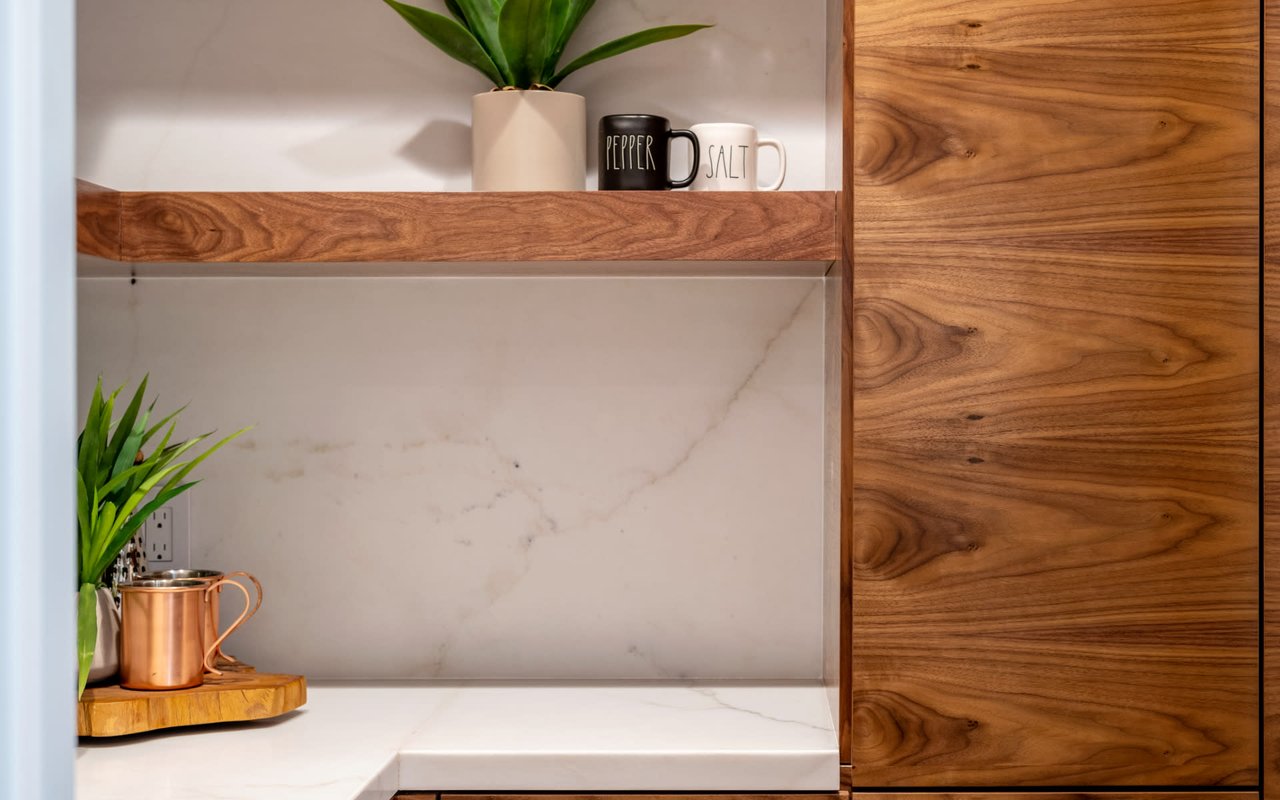Kitchen nook with walnut cabinetry, marble-look backsplash, and a copper mug on the counter.