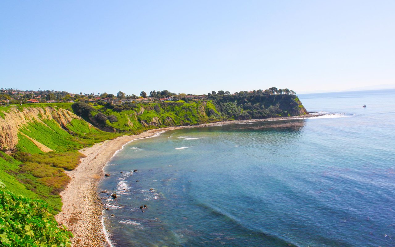 Sunlight paints a secluded beach paradise. Lush cliffs cradle turquoise waters, perfect for swimming and sunbathing.