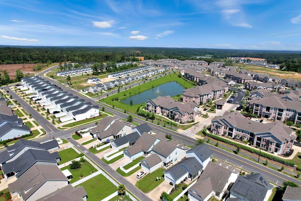 An aerial view of the Canopy community, showing a planned neighborhood with rows of houses and green spaces.