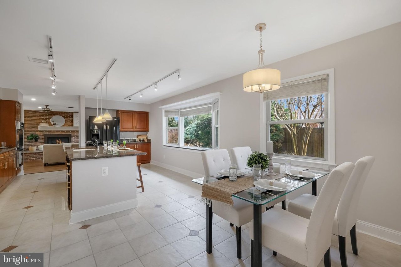 Kitchen and dining area with a large island, glass table, and brick fireplace in the adjoining living room.