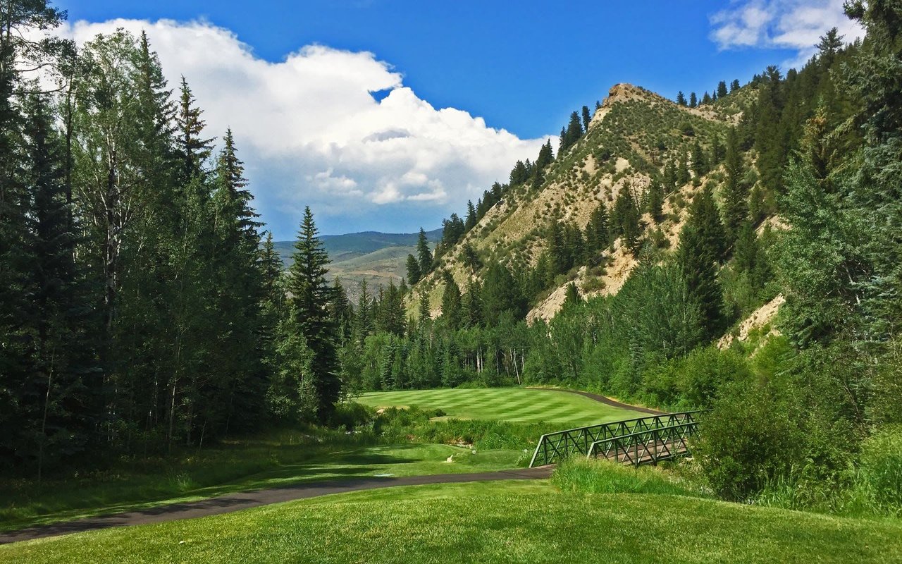 A scenic golf course with a bridge crossing a small stream