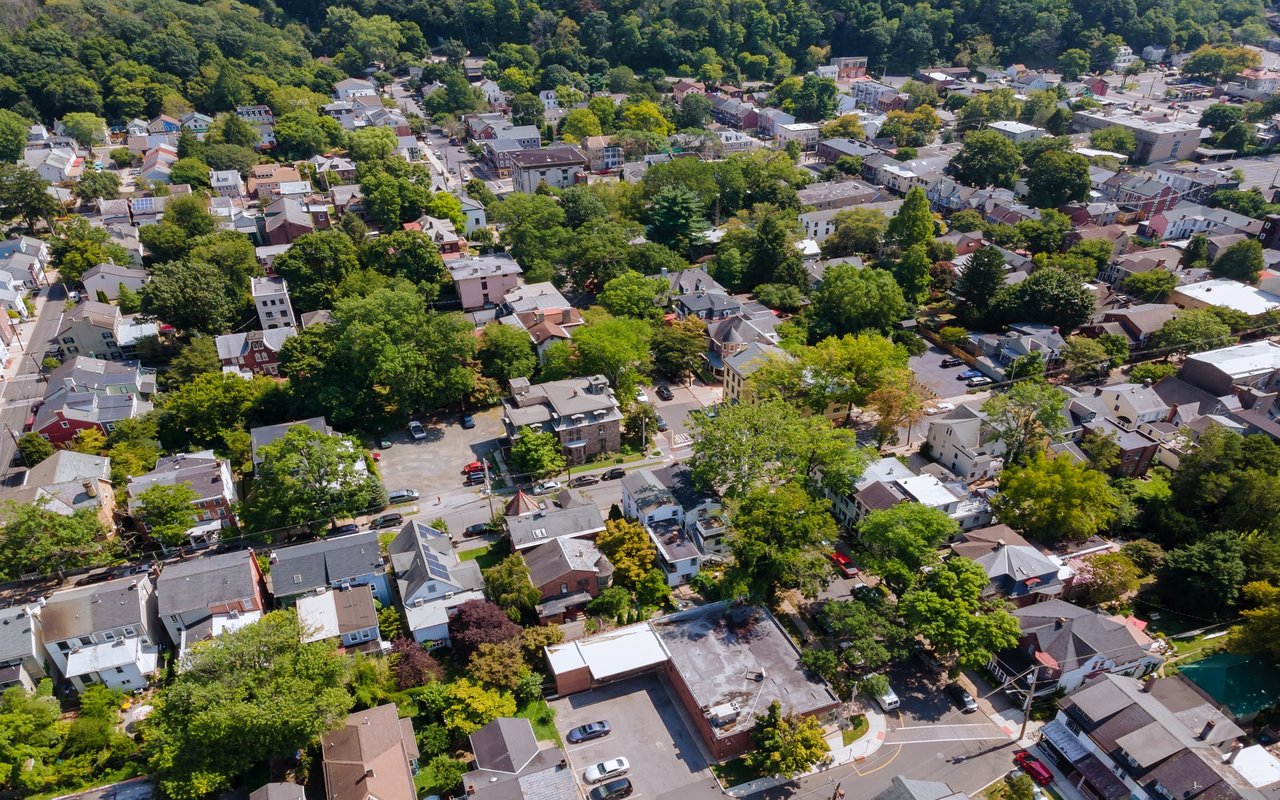 An aerial view of a residential area with colorful houses, trees, driveways, and winding streets.