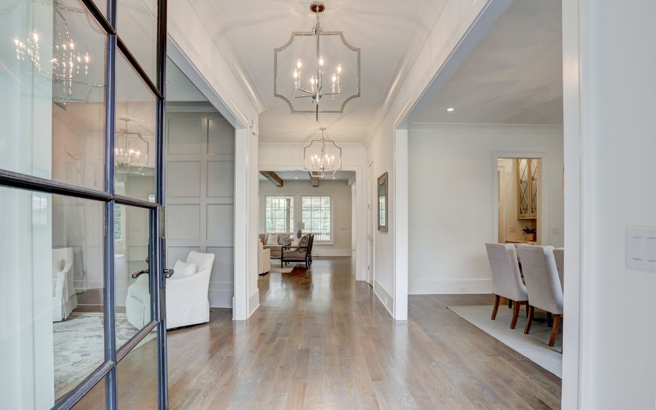 A long hallway with wooden floors and chandeliers hanging from the ceiling