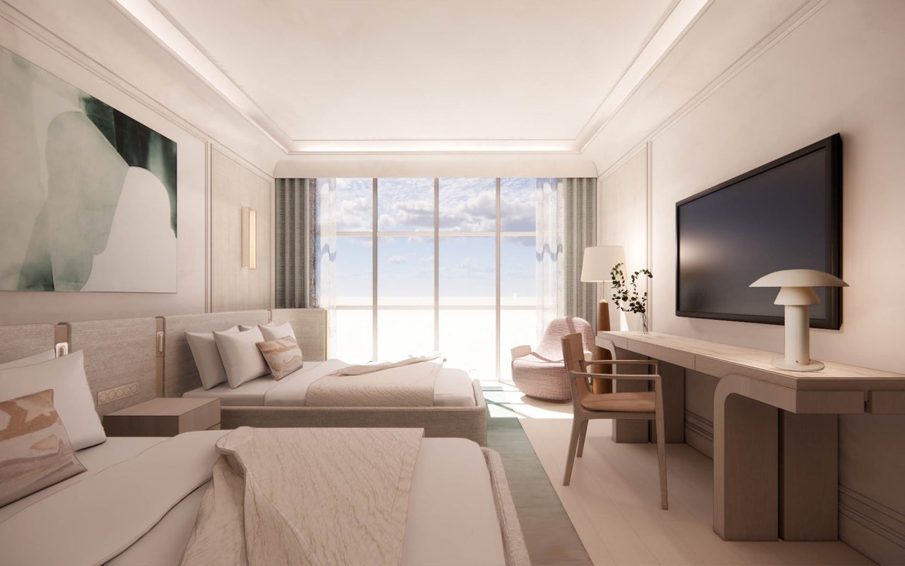 Staged bedroom with two beds, a desk, and floor-to-ceiling windows overlooking the water.