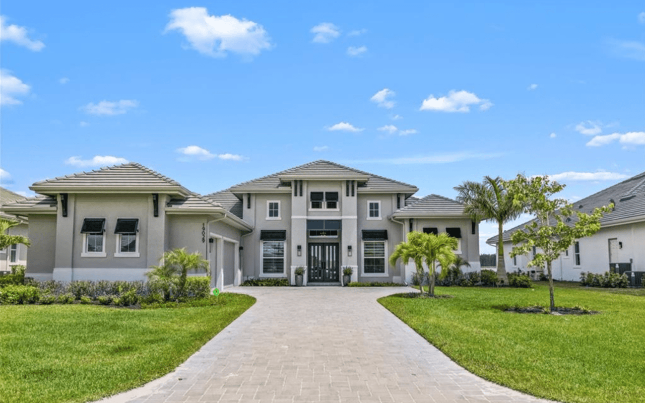 The house features multiple gables, large dark-framed windows, and a grand entrance with dark double doors.