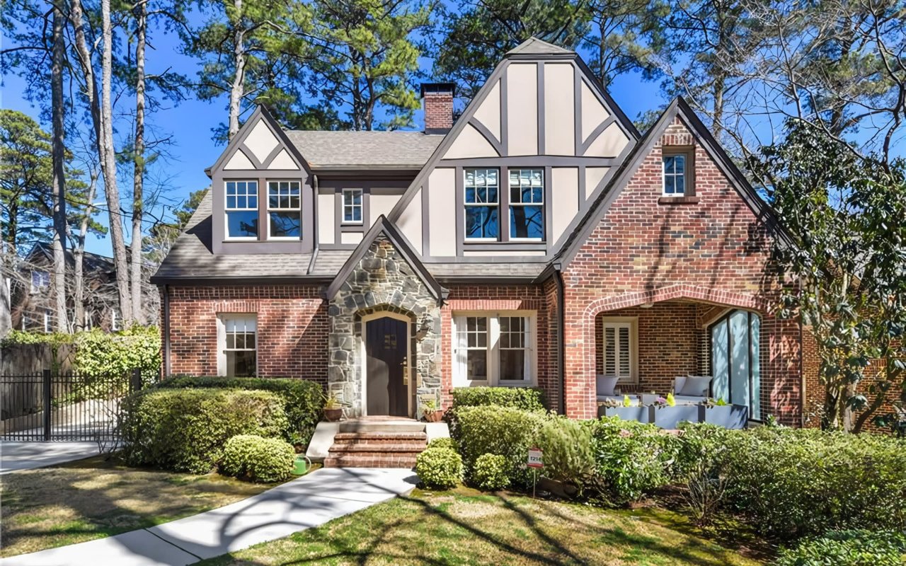 Two-story red brick house with a stone pathway, a slate roof, a chimney, a covered porch, and a two-car garage on the left.