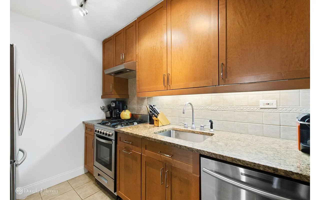 Kitchen with warm wood cabinets, granite counters, white tile backsplash, and stainless steel appliances.