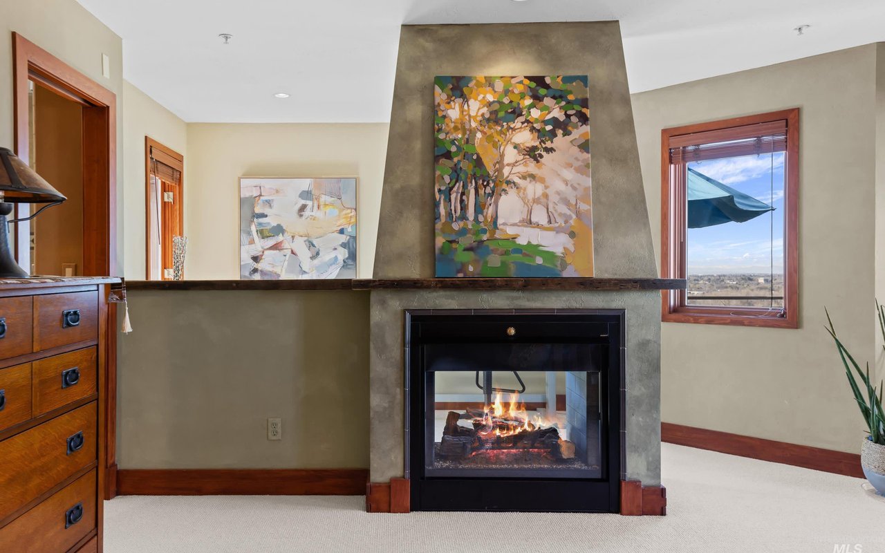 The double-sided fireplace and pony wall in the primary suite. On the other side is the owner's reading and art nook.