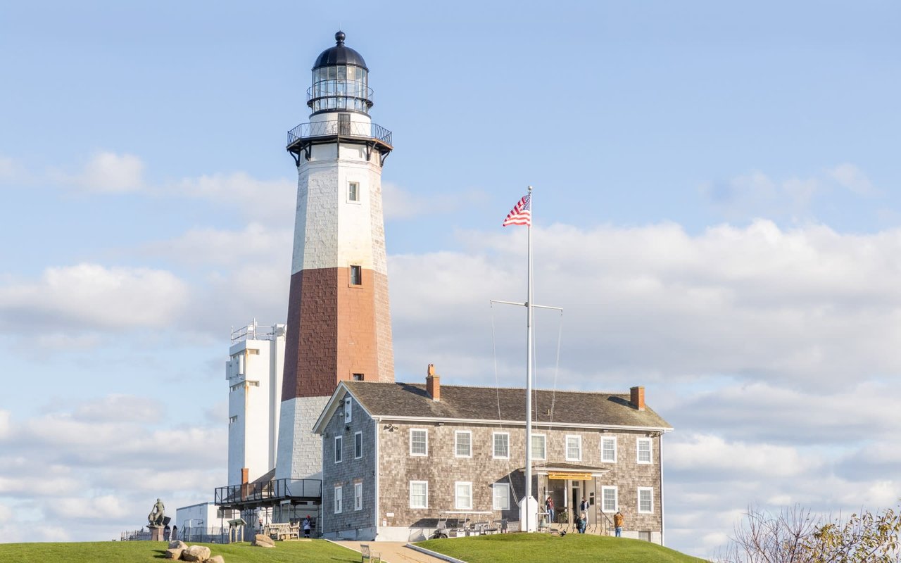 A lighthouse sitting on top of a hill, with a house next to it