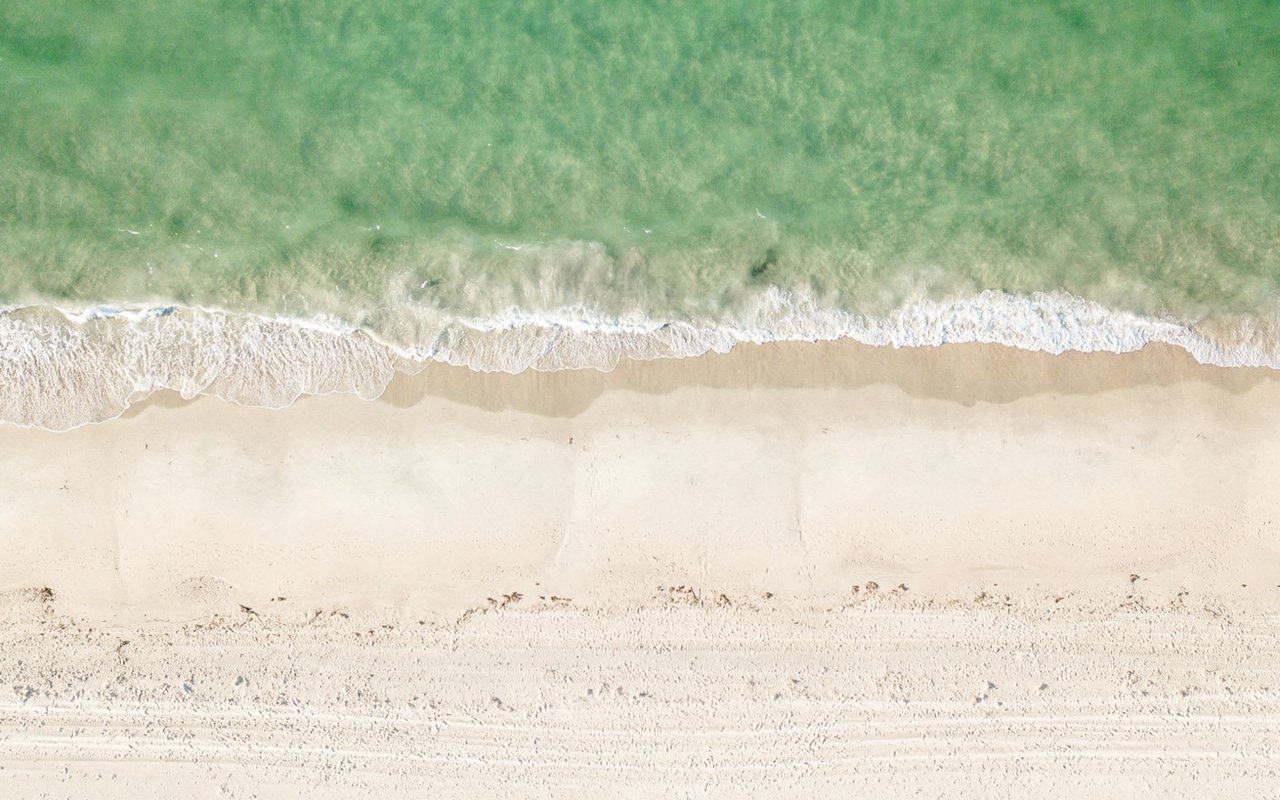 Ariel view of waves crashing on a white sandy beach in Quidnet.