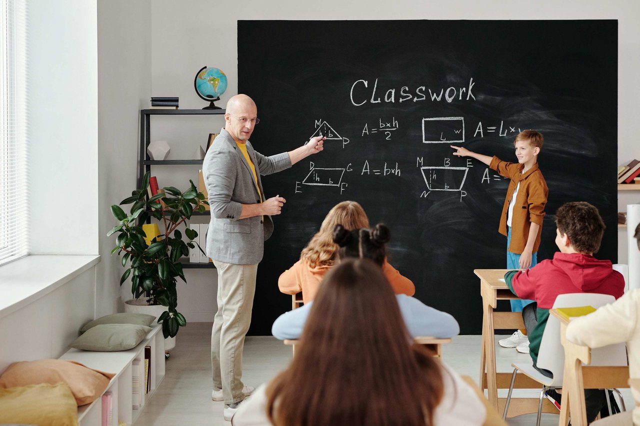 A teacher and student solving geometry problems on the chalkboard during a math class at one of the schools in Lake Nona, with attentive students seated in the classroom