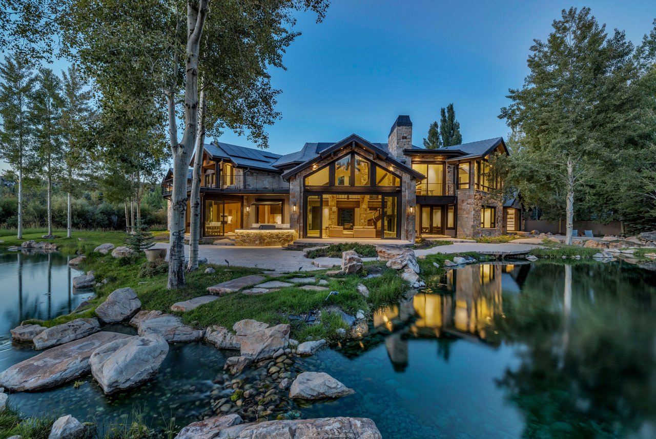 A large, luxurious house with stone and wood siding, featuring large windows
