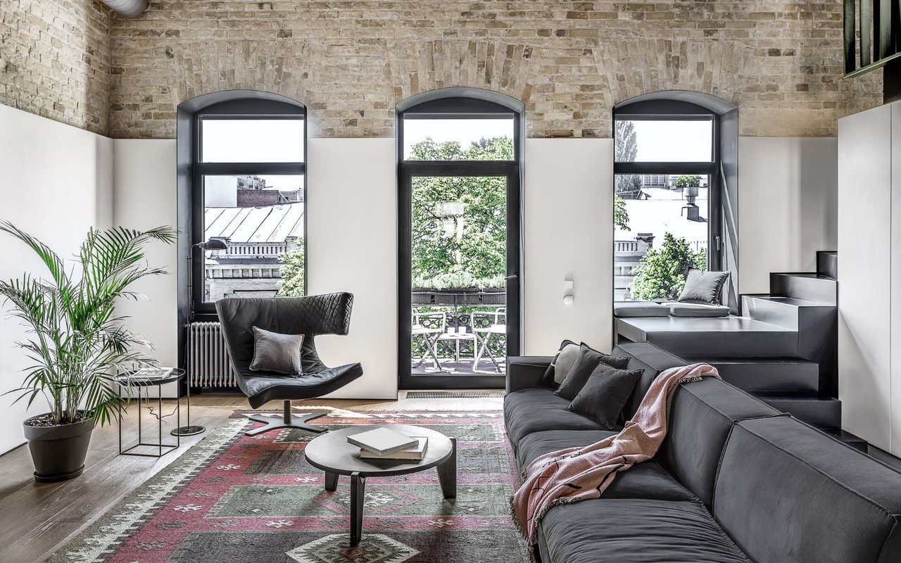 A spacious, industrial-chic loft apartment with high ceilings and exposed brick walls.