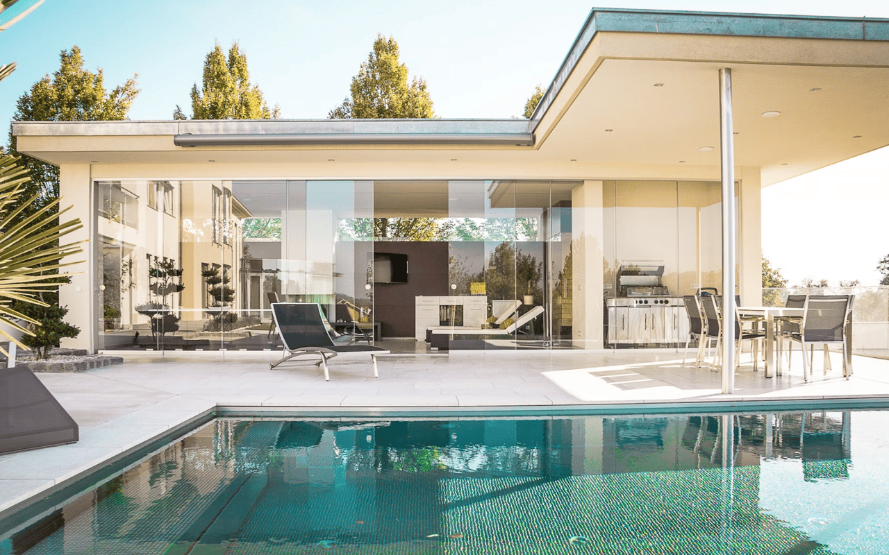 Sun-kissed modern home with pool, lush greenery, and serene blue sky.