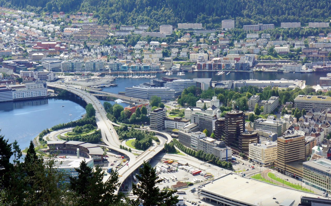 An aerial view of a complex highway interchange with multiple lanes, bridges, and tall buildings in the background.