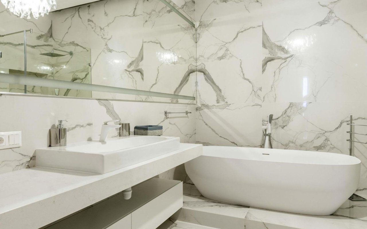 A bathroom with a bathtub, sink, and a large mirror.