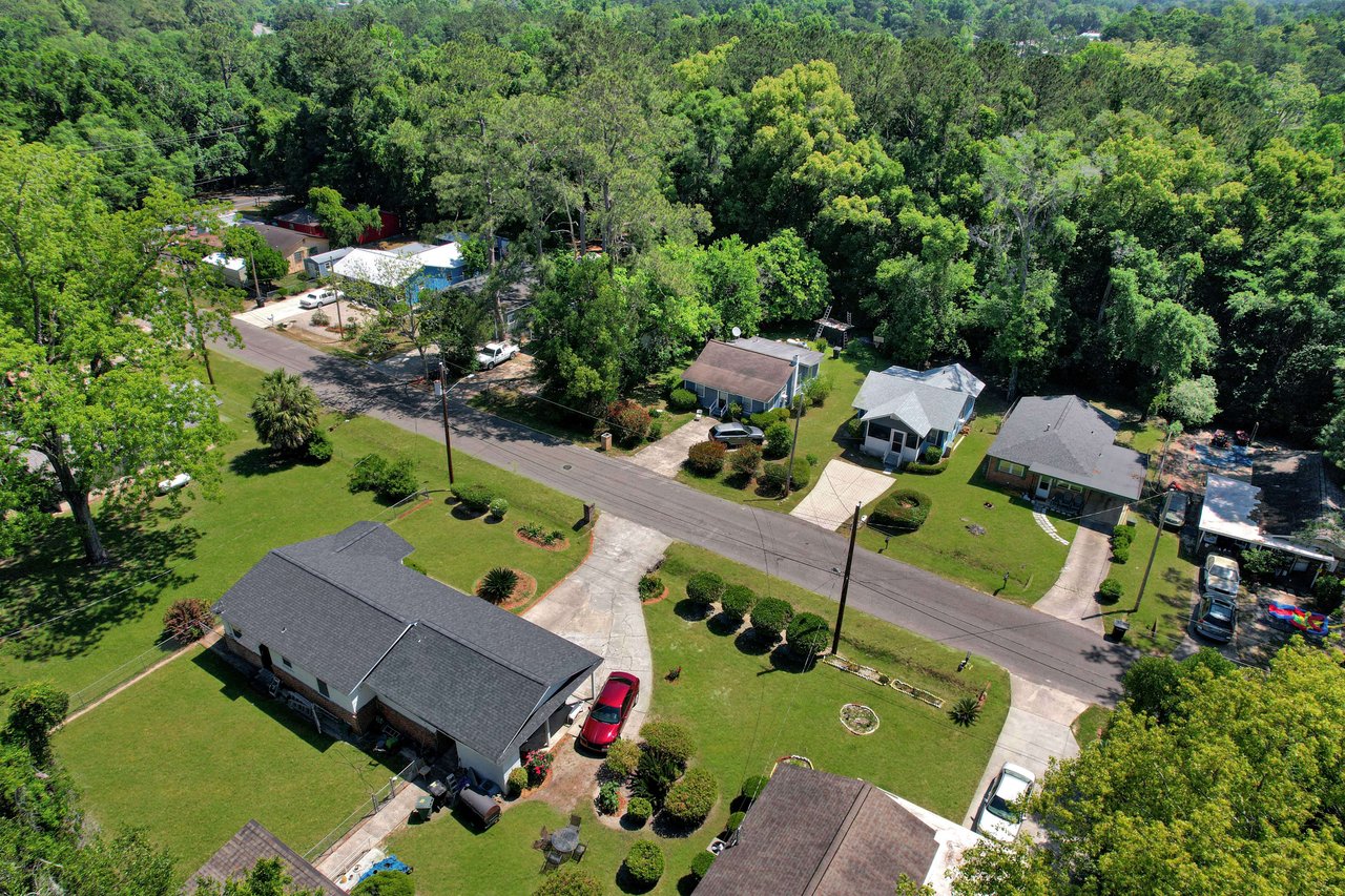 An aerial view of liberty park showing multiple houses with yards. The area is surrounded by trees, giving it a lush, green appearance.