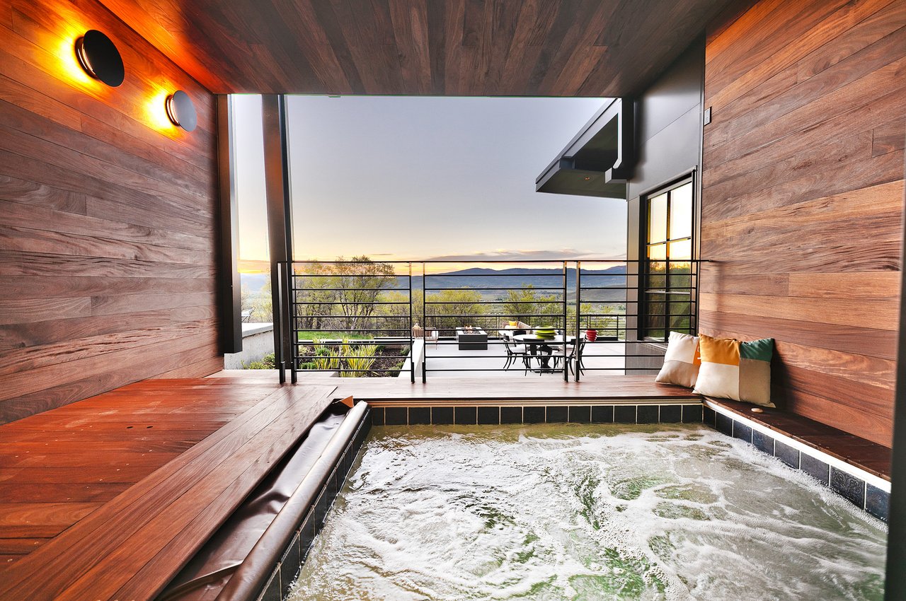 A modern hot tub on a patio with a scenic view of a valley and mountains at dusk