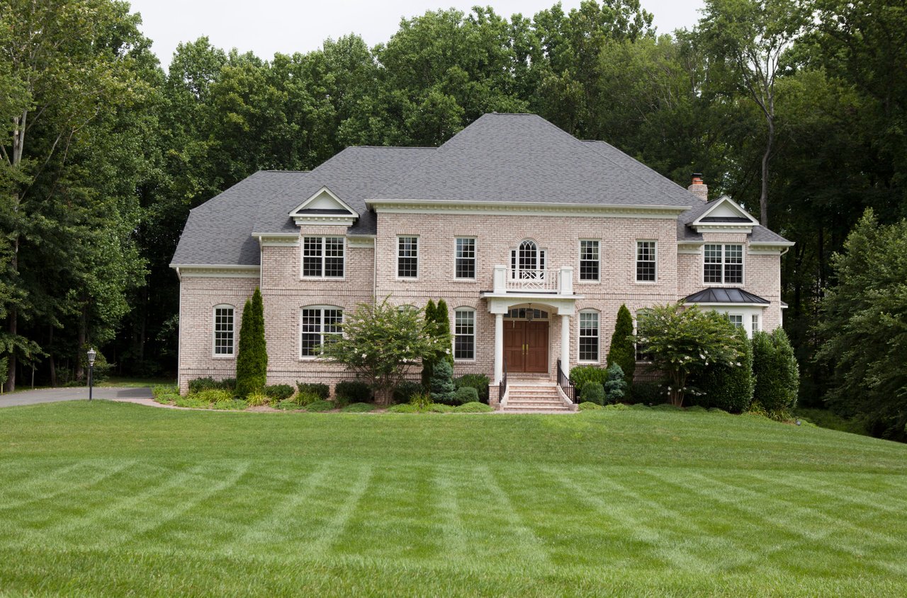 Large brick house with a large green lawn in front of it.