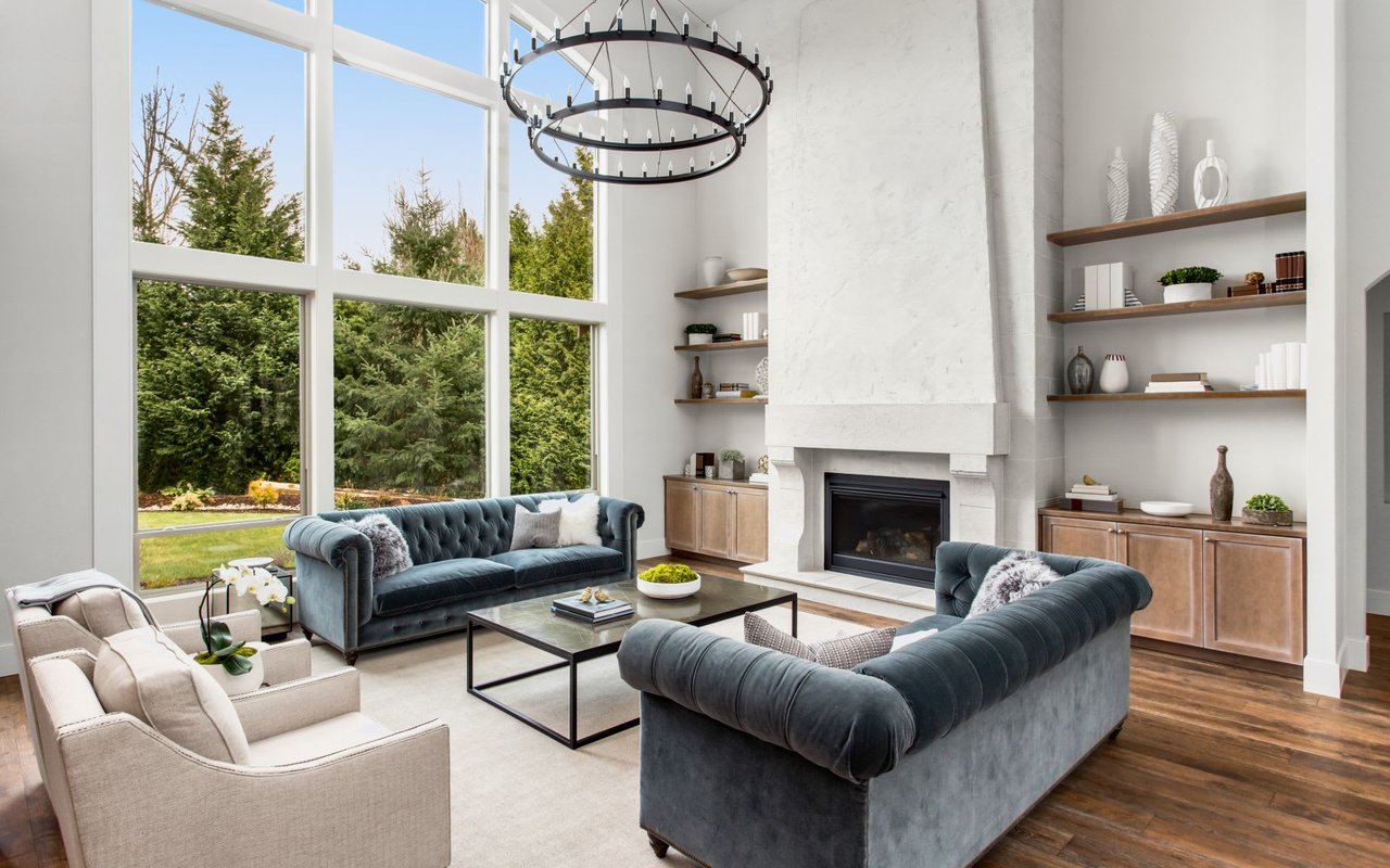 Modern living room with high ceilings, large windows, and elegant blue velvet sofas.