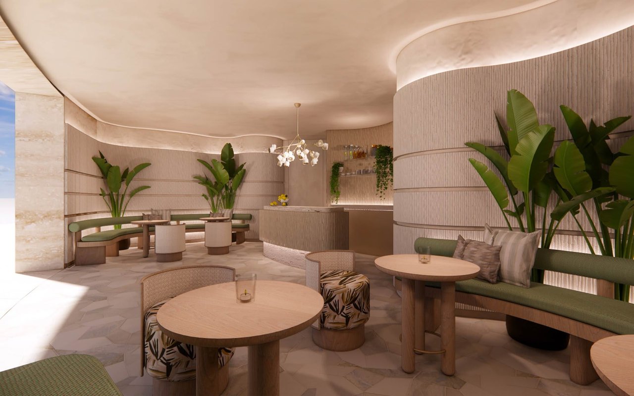 Furnished lounge with curved green seating, round tables, tropical plants, and a bar counter.