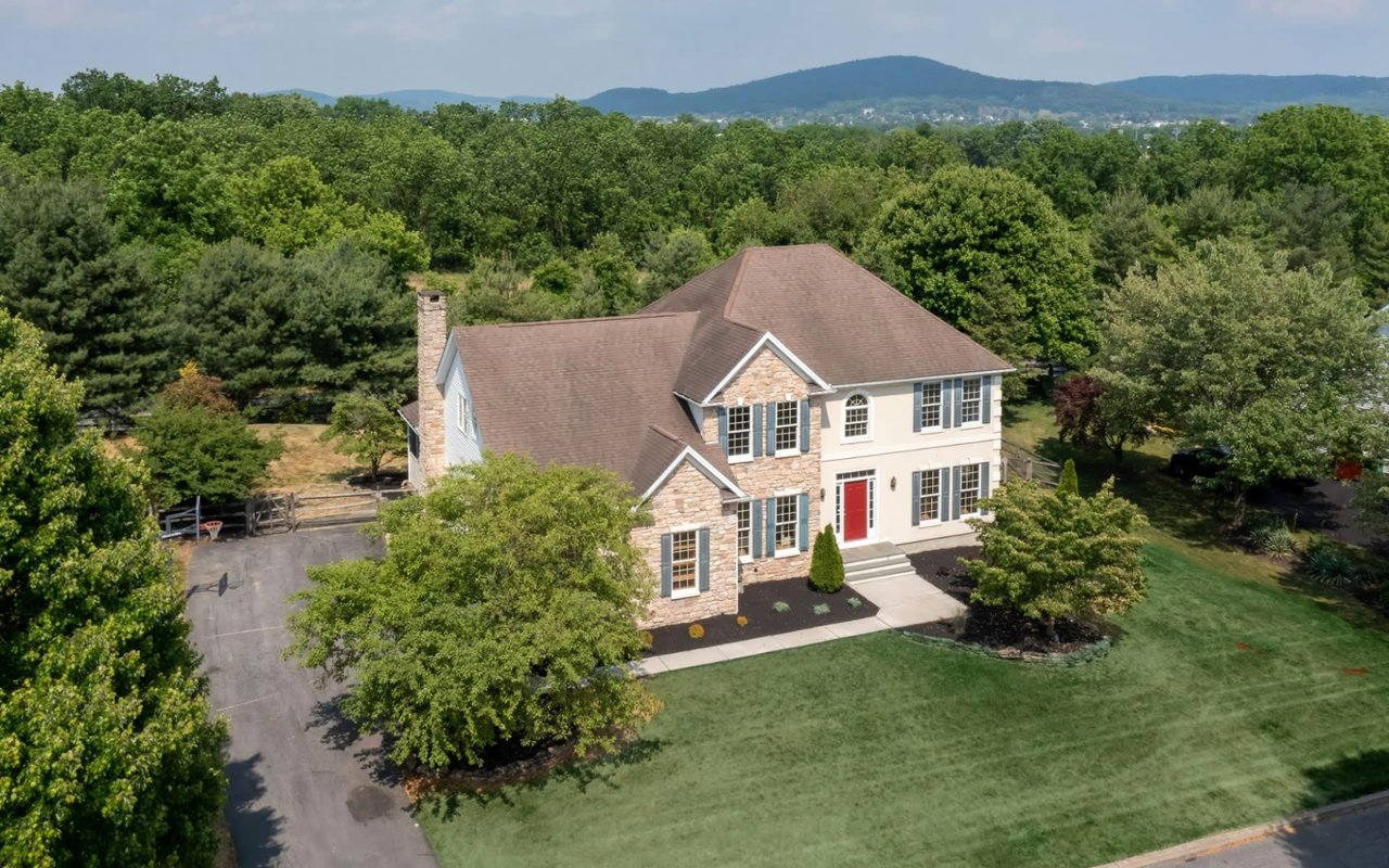 Aerial view of a house with a red door in a green field.