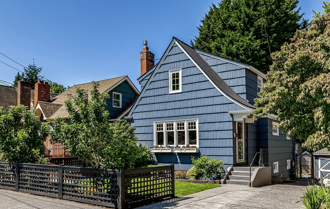 dark blue home with black fence and a long driveway