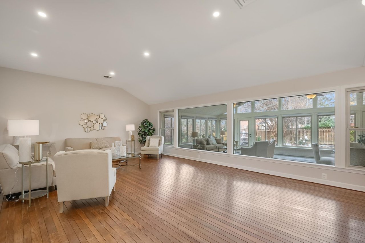 Living room with wood floors, neutral seating, and a wall of large windows.