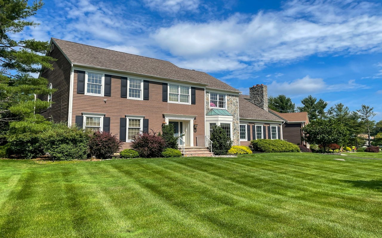 A large two-story brick house with a green lawn