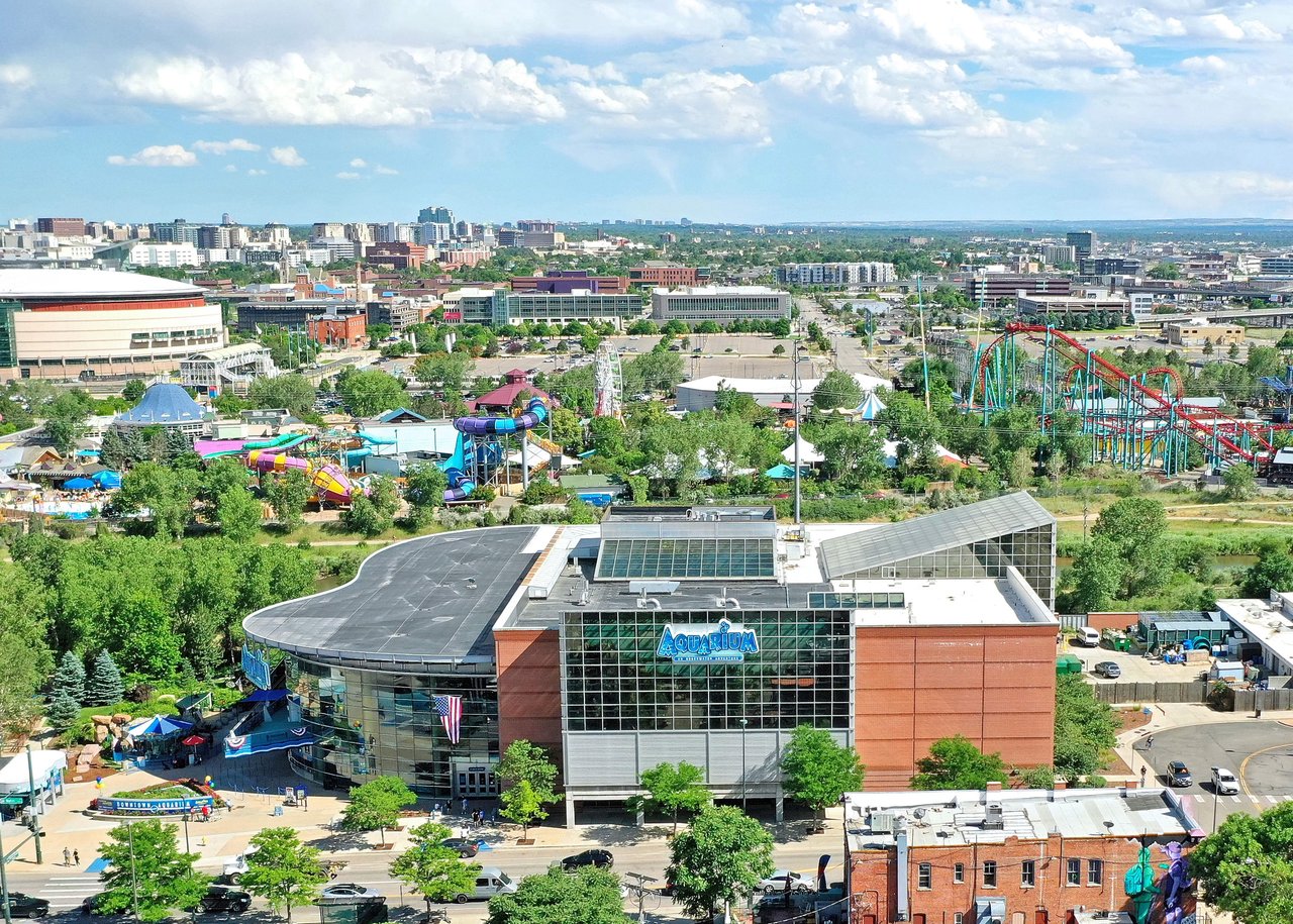 Aerial view of an amusement park with a large Ferris wheel, roller coaster, and colorful buildings