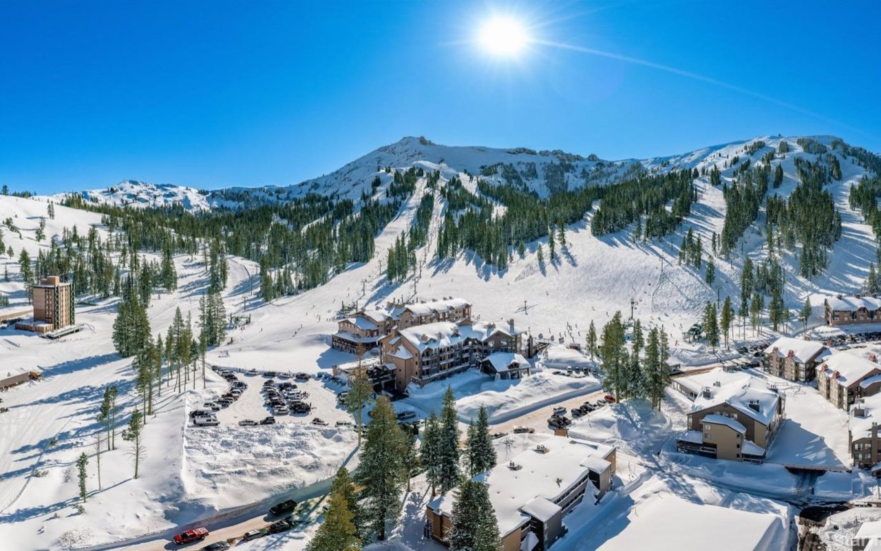  A picturesque winter scene featuring snow-covered slopes, a ski lodge, and surrounding mountains.