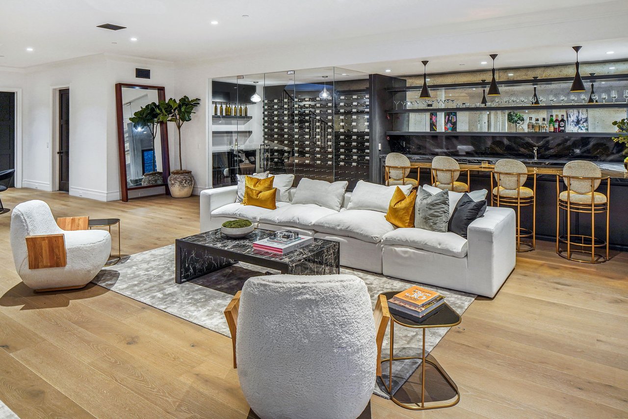  A spacious and modern living room featuring a large white sectional sofa with yellow and dark throw pillows. 