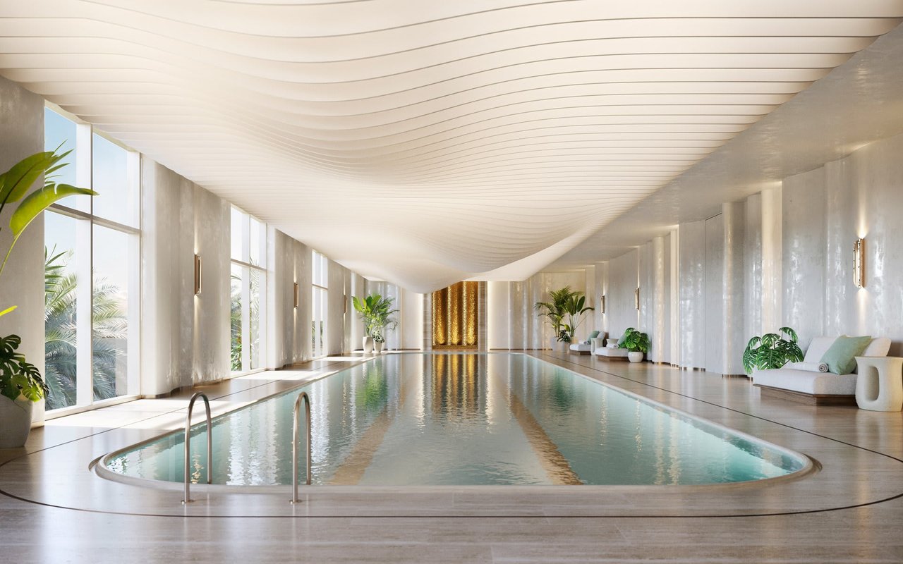 Indoor pool with a wave-pattern ceiling, tall windows, and lounge seating.