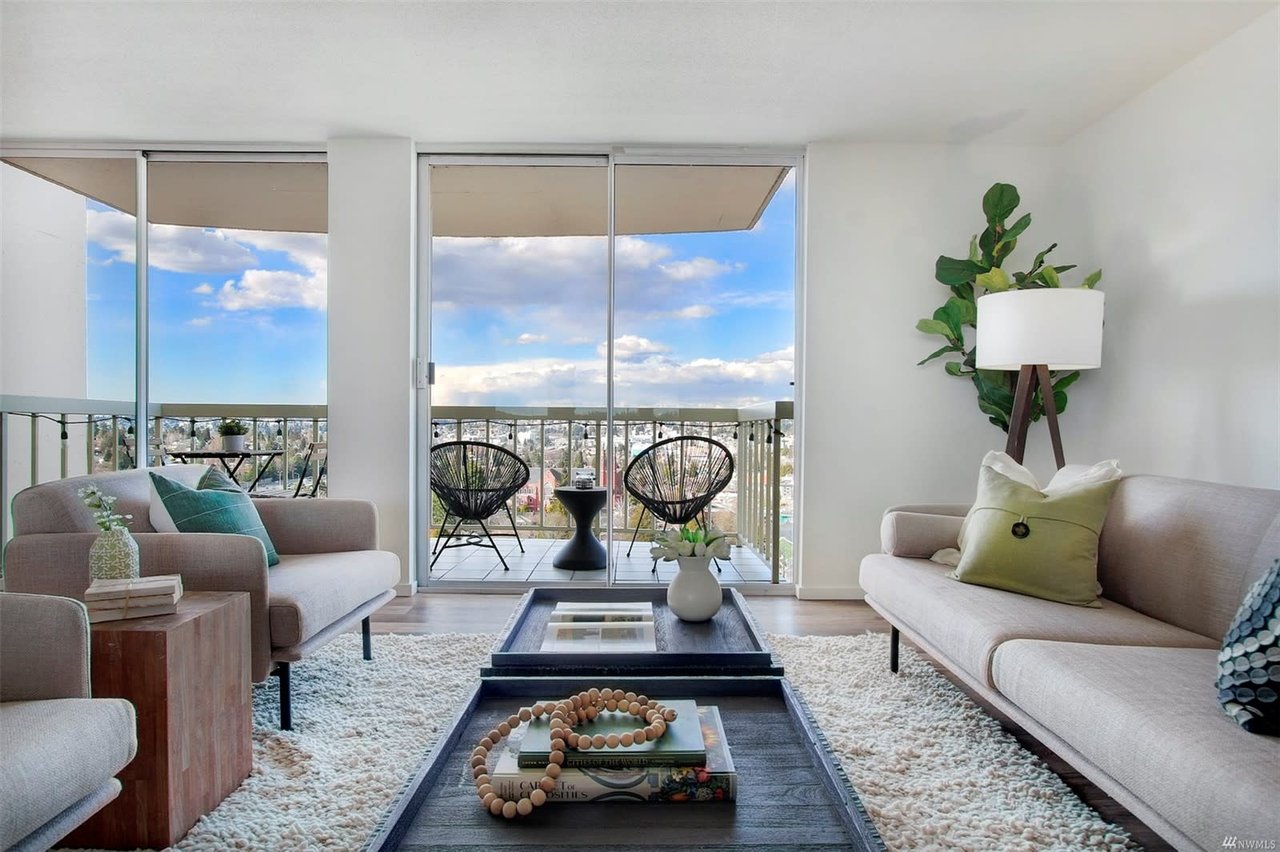 Stylish condo interior with cozy furnishings, floor-to-ceiling windows, and a balcony offering panoramic views.