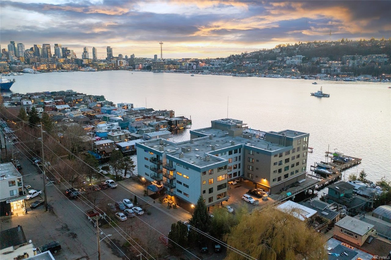 Waterfront luxury condos at dusk with the city skyline in the background, highlighting exclusive living with a view.