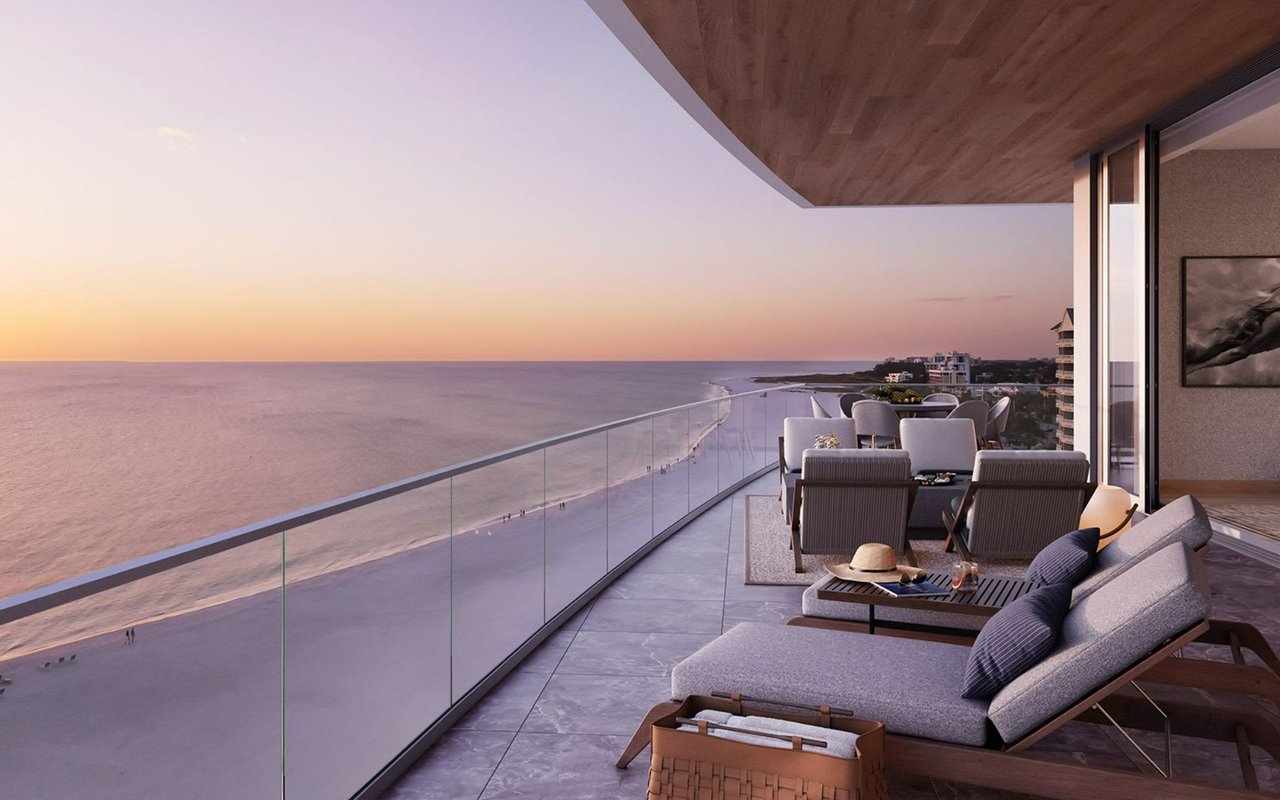 A large balcony with a glass wall overlooking the ocean.