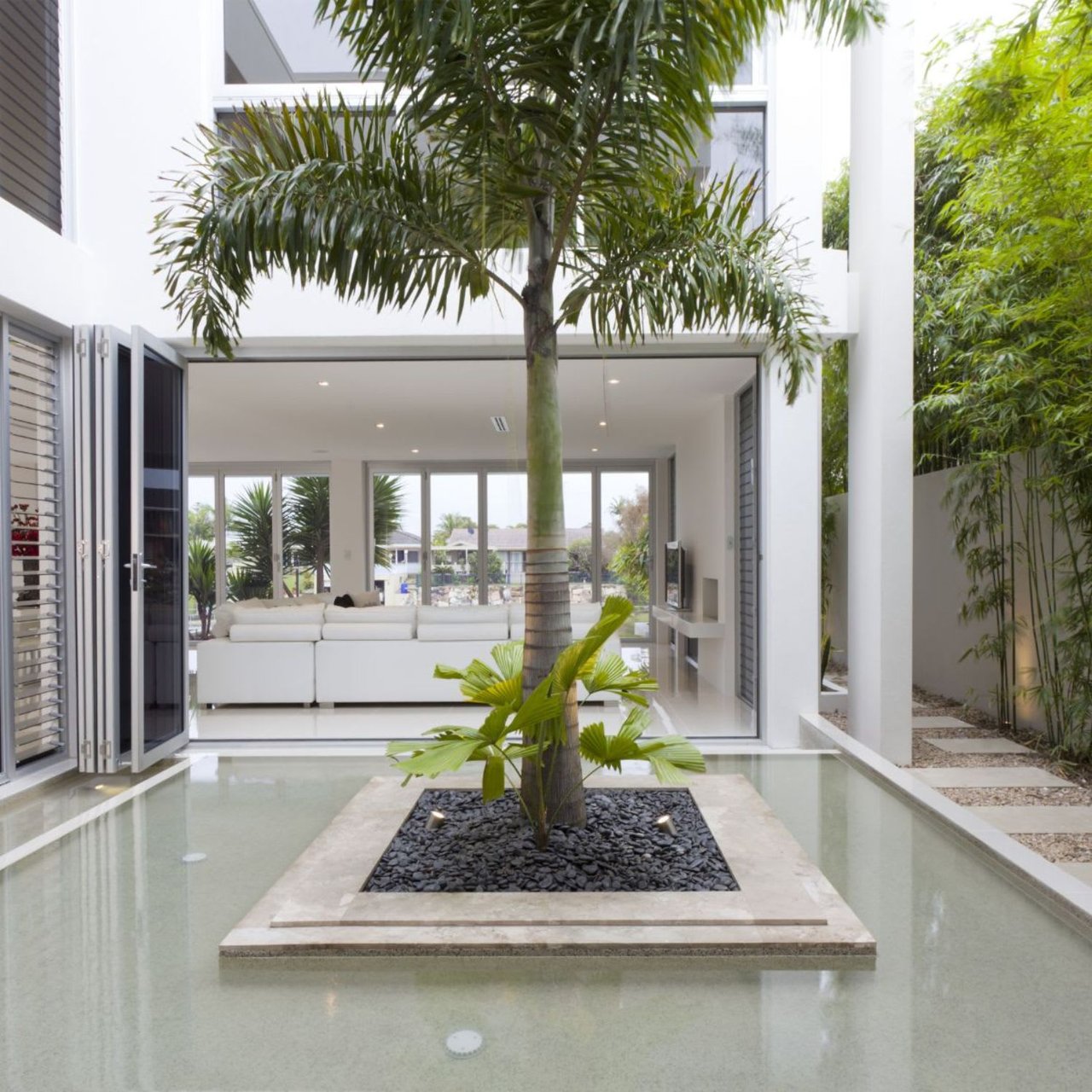  A modern, minimalist house featuring a central outdoor courtyard with a shallow reflecting pool. 
