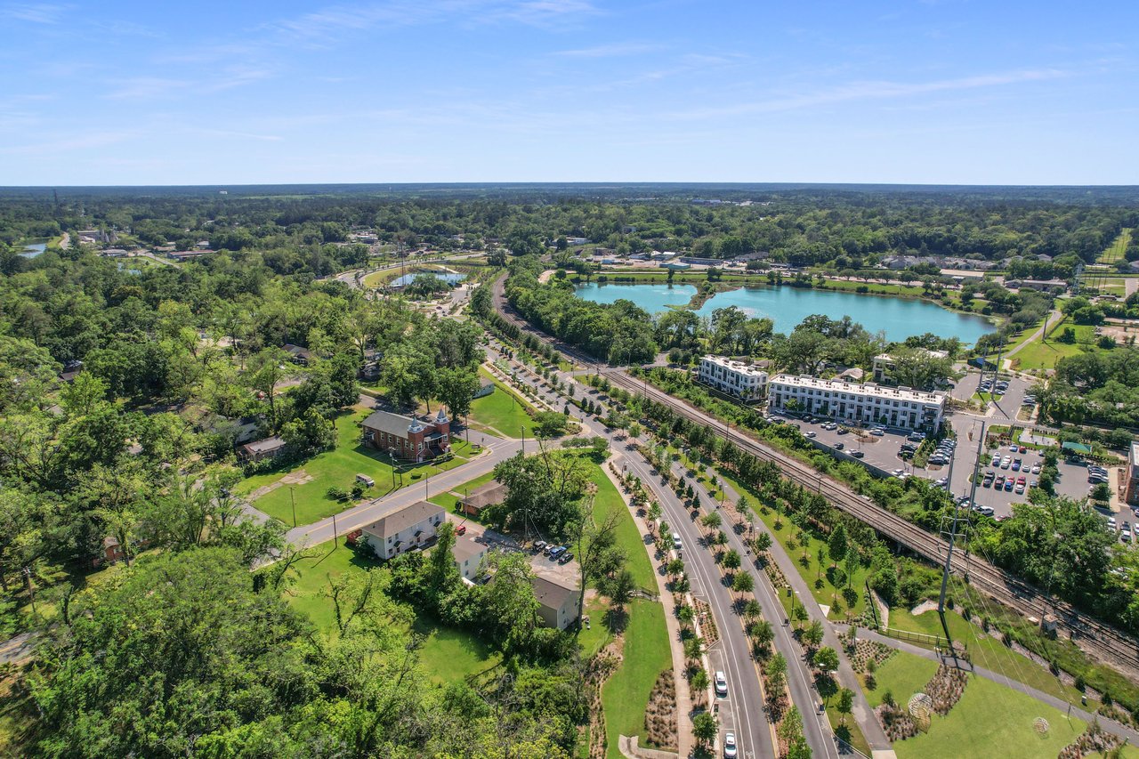 Another aerial view of Villa Mitchell, highlighting a large water feature or pond, roads, and nearby structures. The community has a picturesque setting with plenty of greenery.