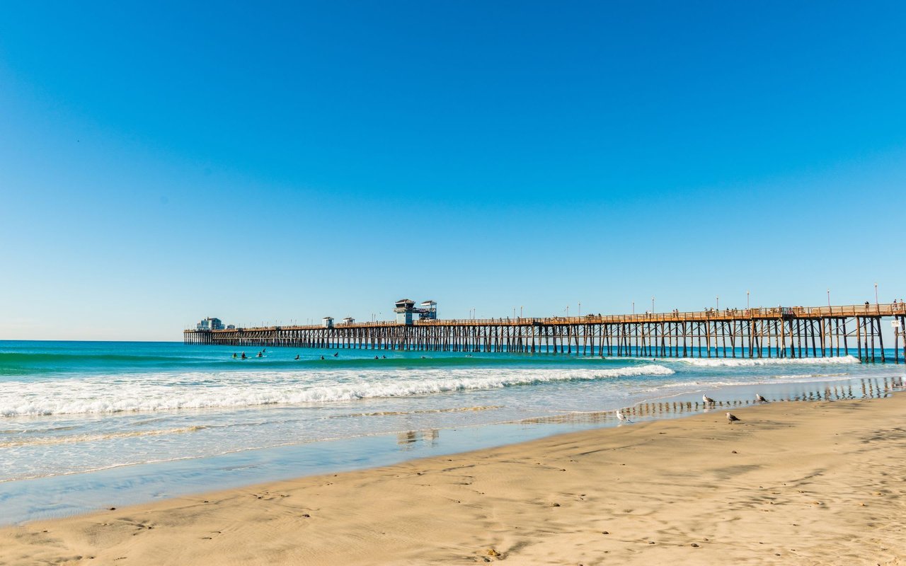 A beach with a long wooden pier overlooking the ocean