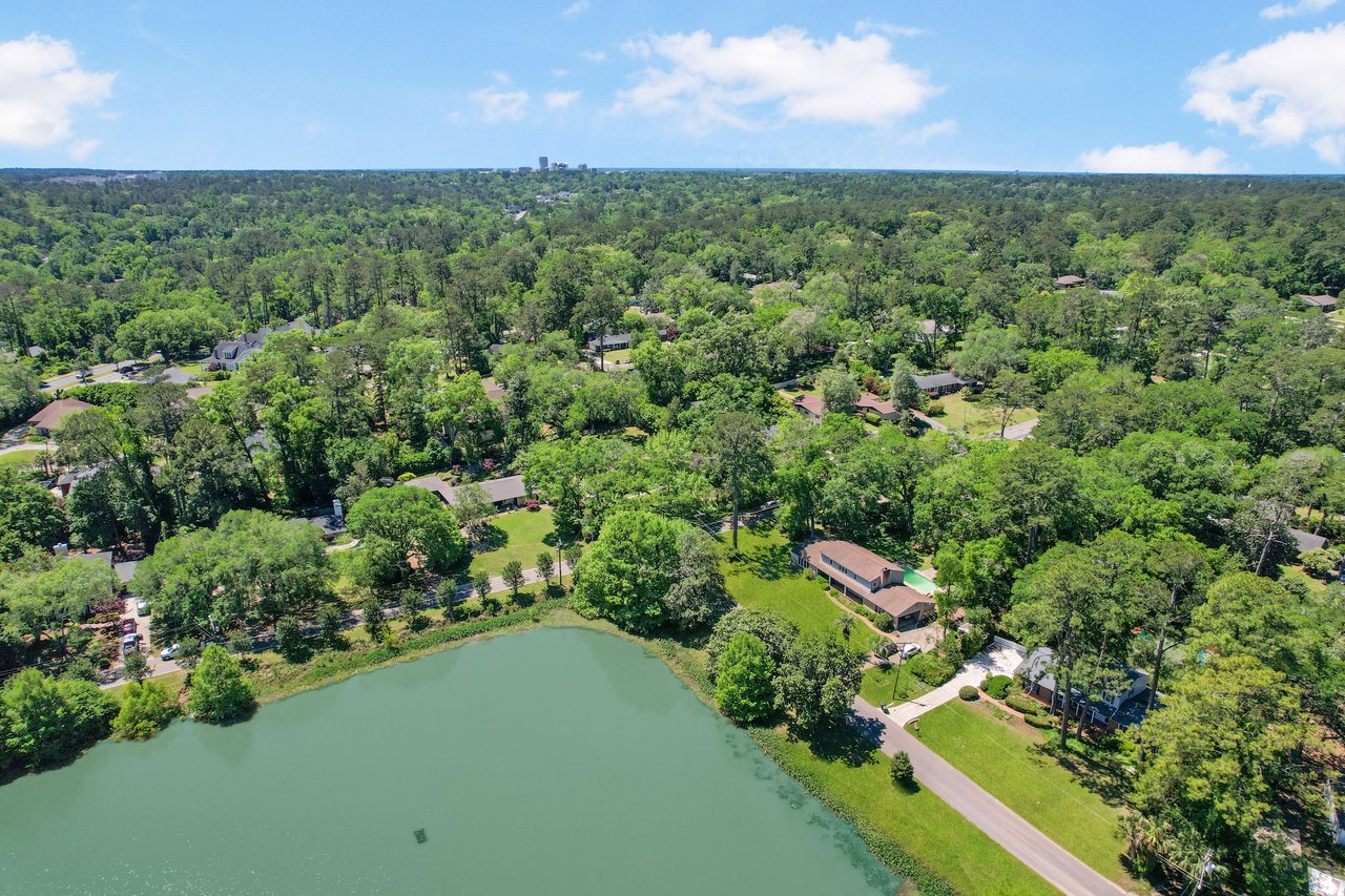 An aerial view of a residential neighborhood in Waverly Hills with a pond, surrounded by lush greenery.