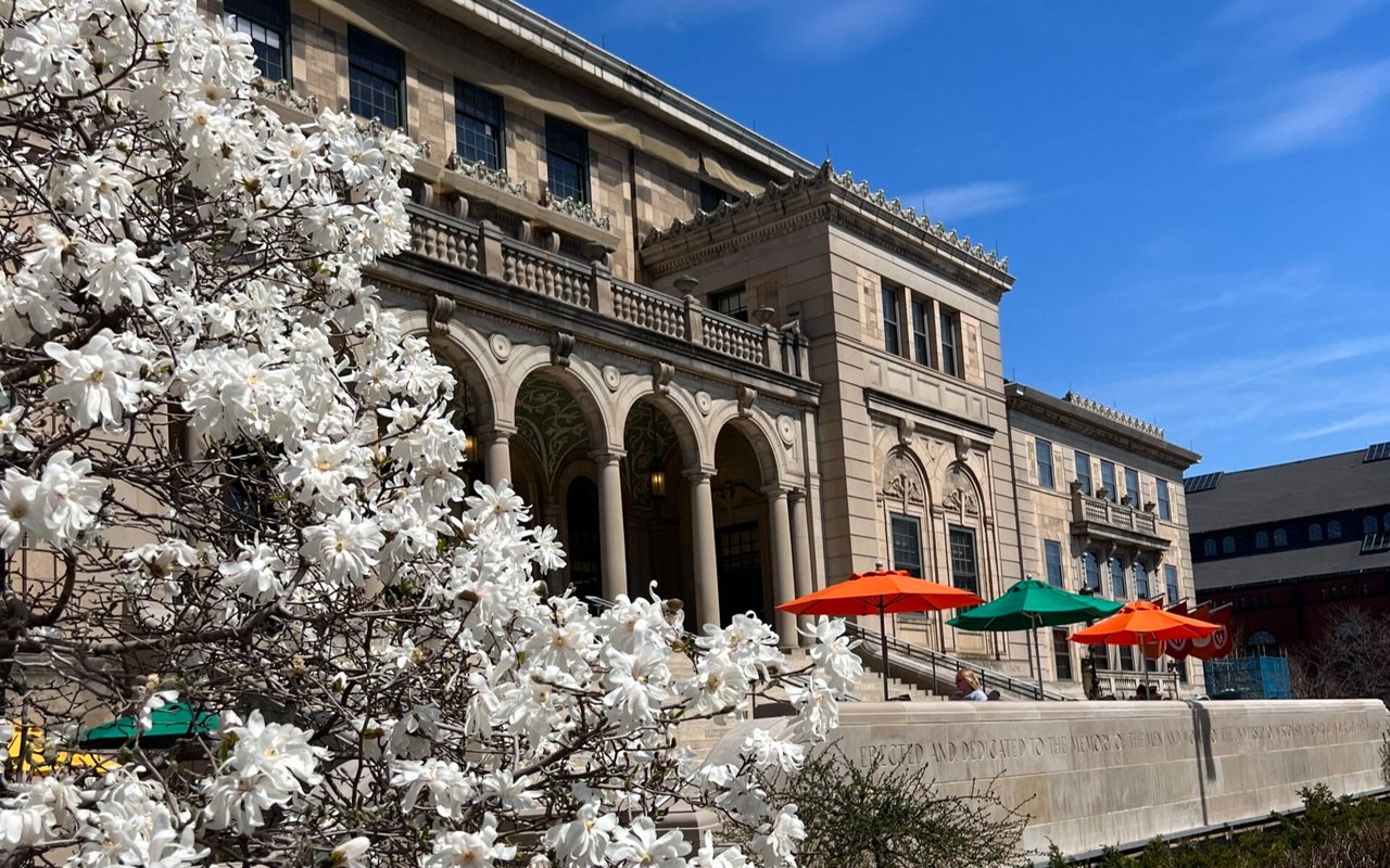 View of the Memorial Union building at the University of Wisconsin-Madison, featuring white flowers, and umbrellas in front.