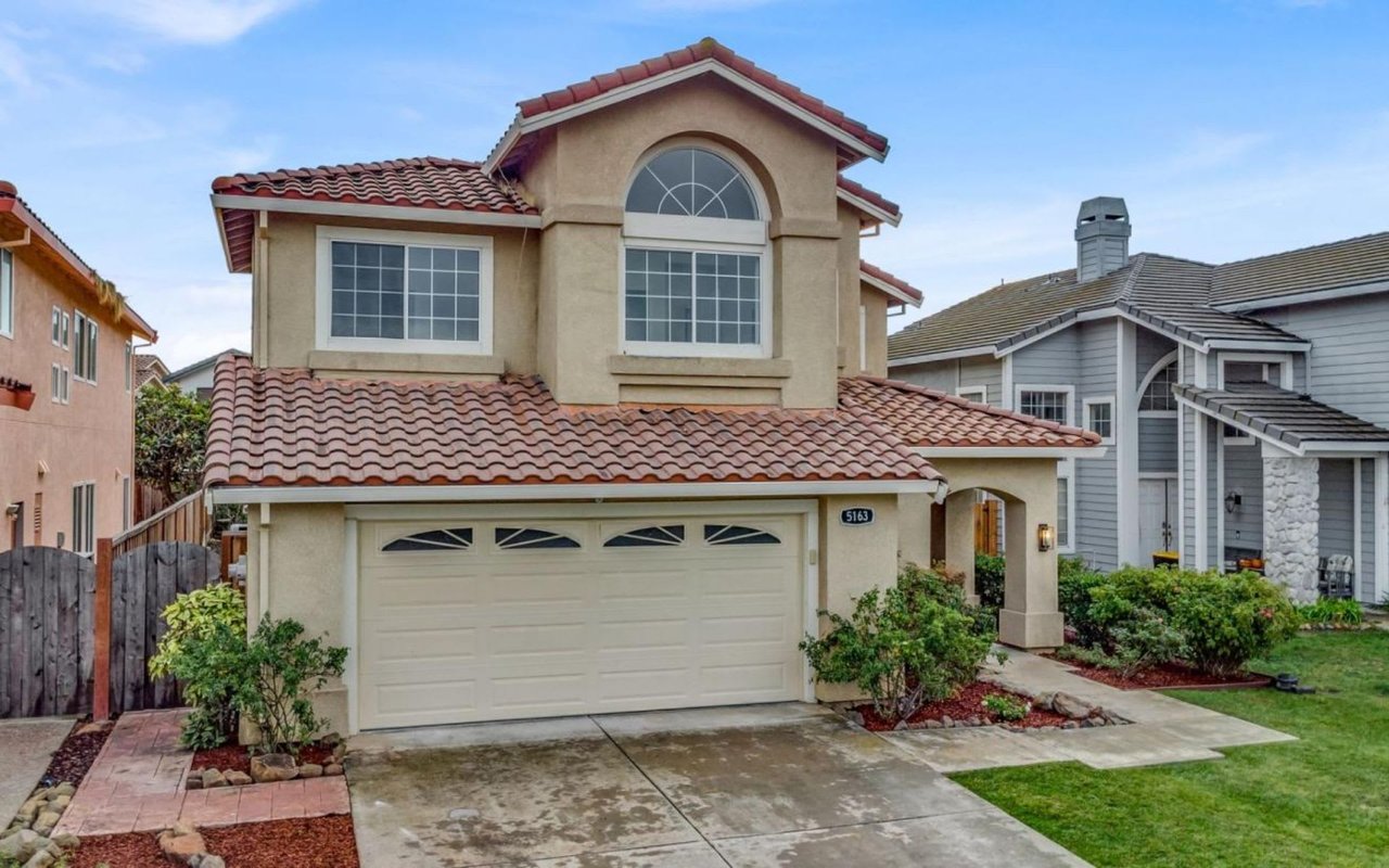 The house features a prominent attached two-car garage with a light-colored door. 