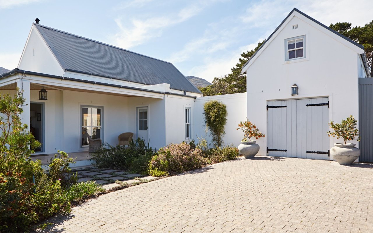 A two-story white house with a fenced backyard, a two-car garage,  a front yard, and a walkway leading up to the porch.