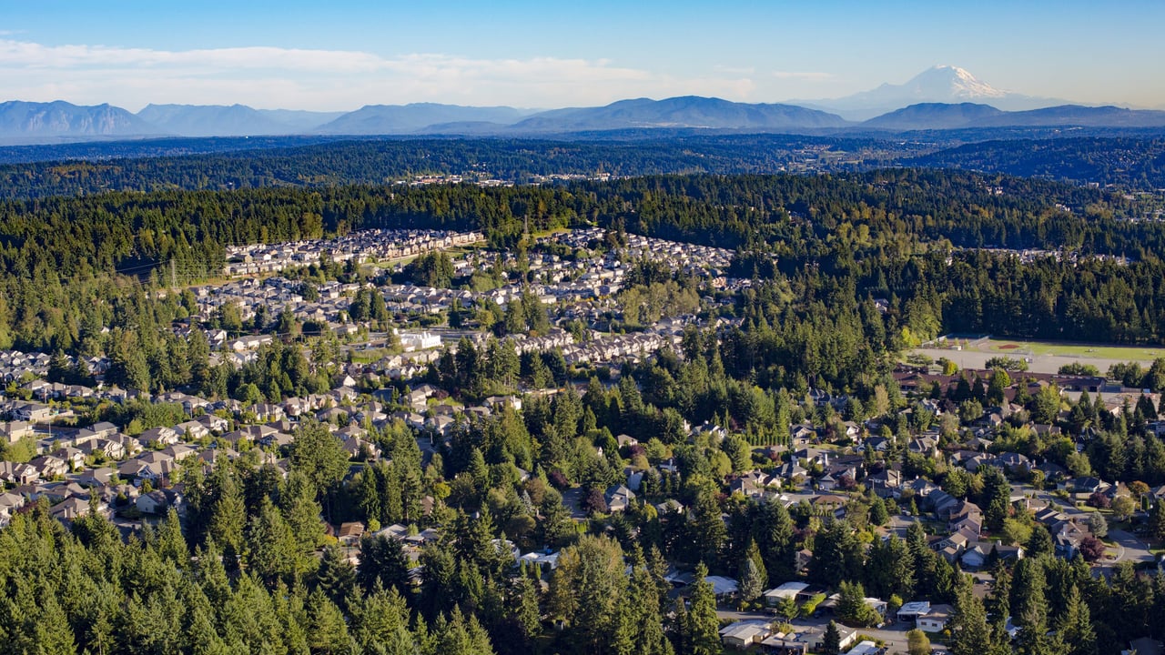 An aerial view of a suburban neighborhood nestled among lush green forests