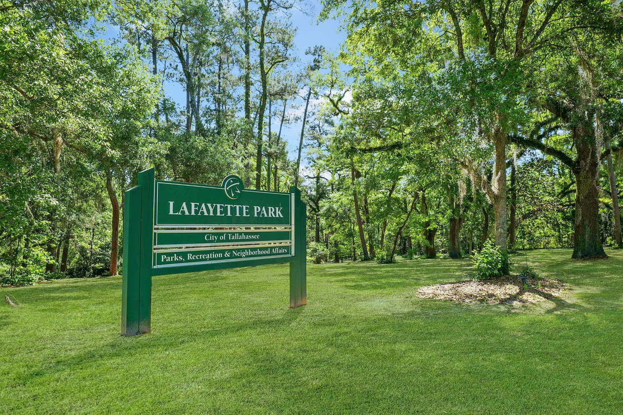 A ground-level view of a sign for Lafayette Park, surrounded by trees and green grass.