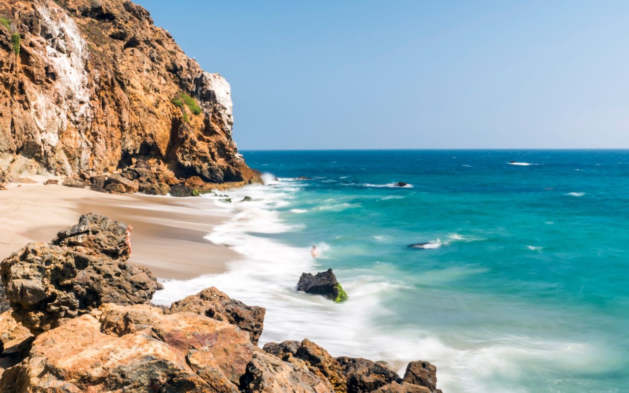 A rocky beach with waves crashing on the shore